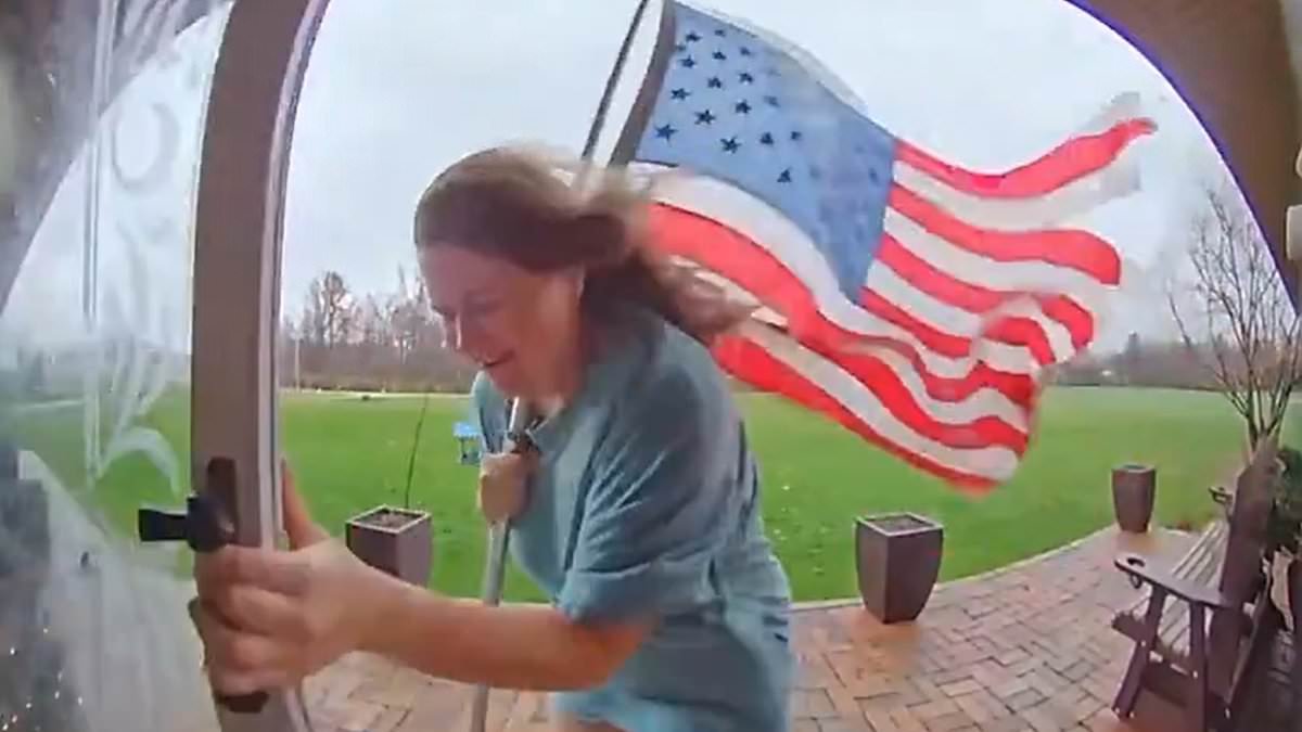 Woman trying to save American flag is nearly blown away in wild winds [Video]